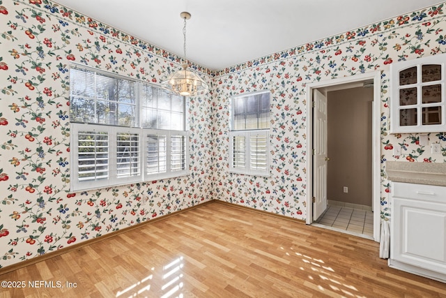 unfurnished dining area featuring hardwood / wood-style floors and a notable chandelier