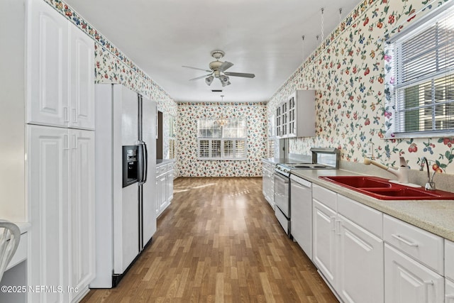 kitchen featuring sink, white appliances, ceiling fan, white cabinetry, and wood-type flooring