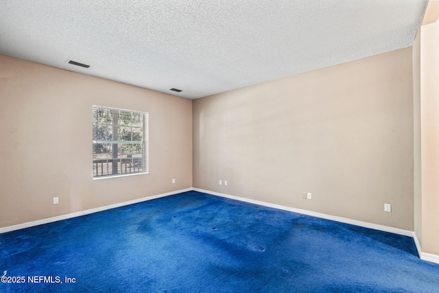 spare room with a textured ceiling and dark colored carpet