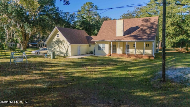 rear view of property featuring covered porch and a lawn