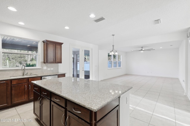 kitchen featuring sink, hanging light fixtures, a kitchen island, light tile patterned flooring, and ceiling fan with notable chandelier