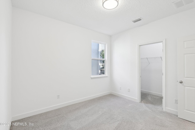 unfurnished bedroom featuring light colored carpet, a walk in closet, and a closet