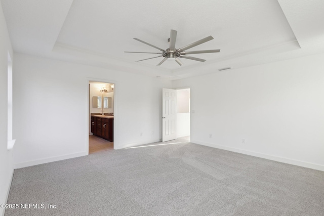 carpeted spare room featuring a raised ceiling and ceiling fan