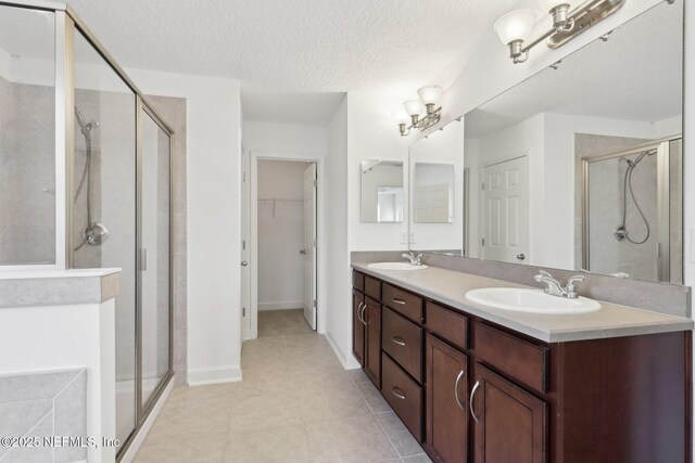 bathroom with tile patterned flooring, vanity, an enclosed shower, and a textured ceiling