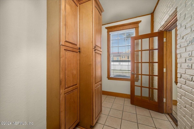 entryway with light tile patterned floors and brick wall