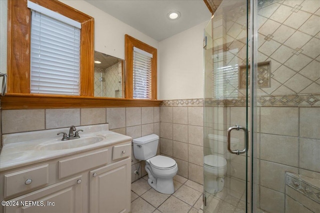 bathroom with tile walls, vanity, an enclosed shower, toilet, and tile patterned floors