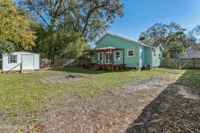 back of house with a storage shed, cooling unit, and a yard