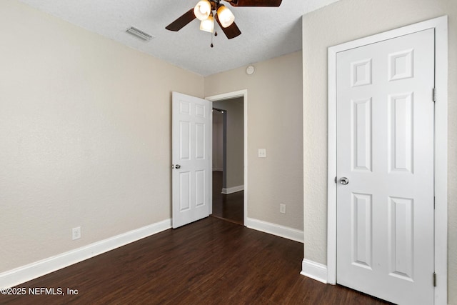 unfurnished bedroom with ceiling fan and dark wood-type flooring