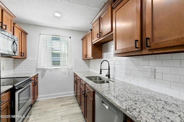 kitchen featuring stainless steel appliances, light stone counters, tasteful backsplash, and sink