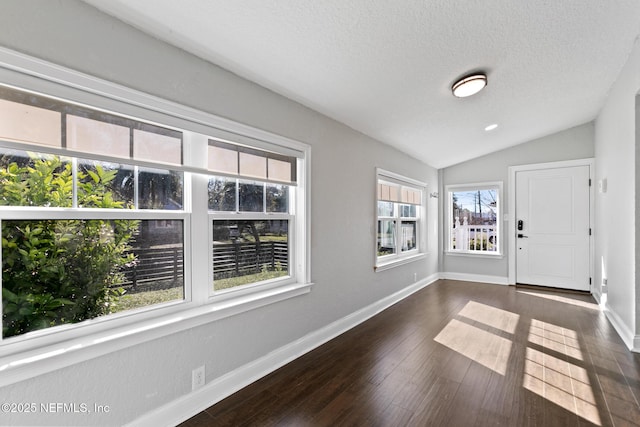 interior space with vaulted ceiling, dark wood-type flooring, a wealth of natural light, and a textured ceiling