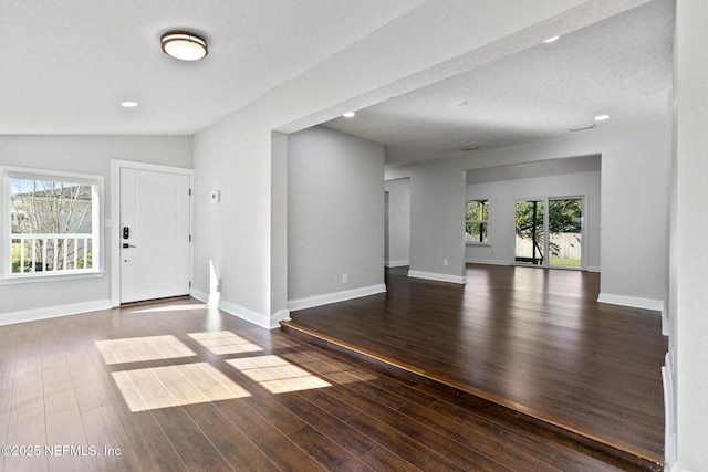 entryway featuring vaulted ceiling, dark wood-type flooring, and a textured ceiling