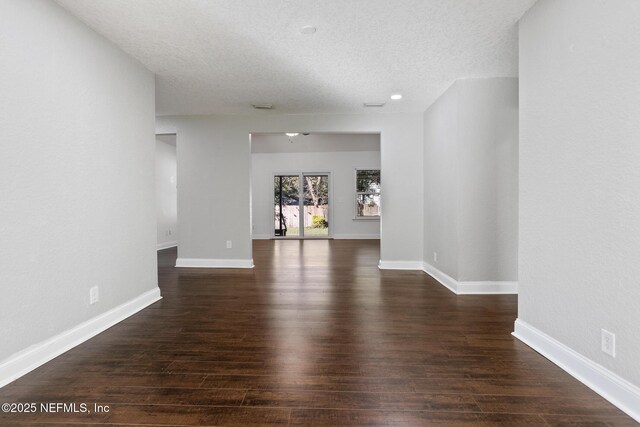 empty room with a textured ceiling and dark hardwood / wood-style flooring