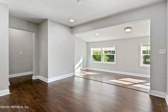 unfurnished room with a textured ceiling and dark hardwood / wood-style floors