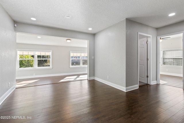 spare room featuring a textured ceiling, ceiling fan, a healthy amount of sunlight, and dark hardwood / wood-style floors