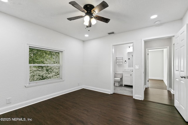 unfurnished bedroom with ceiling fan, dark hardwood / wood-style floors, and connected bathroom