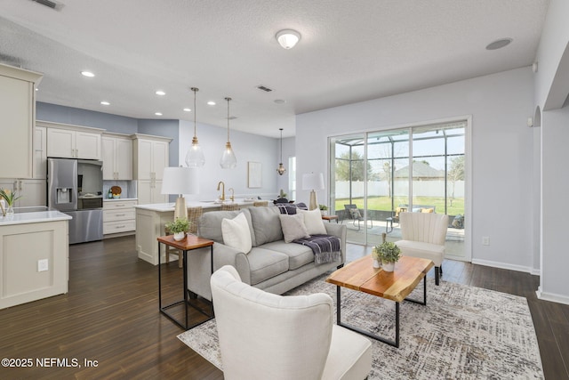 living room featuring sink, dark hardwood / wood-style floors, and a textured ceiling