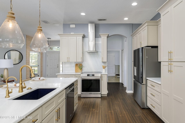 kitchen featuring sink, pendant lighting, stainless steel appliances, decorative backsplash, and wall chimney range hood