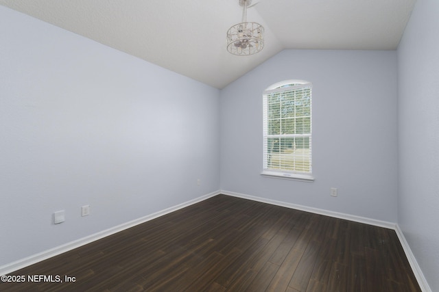 empty room with dark hardwood / wood-style flooring and vaulted ceiling