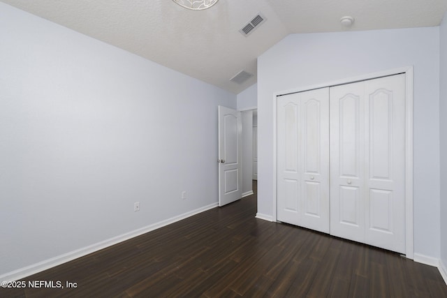 unfurnished bedroom featuring vaulted ceiling, dark hardwood / wood-style flooring, and a closet