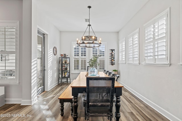 dining room with baseboards, visible vents, a chandelier, and wood finished floors