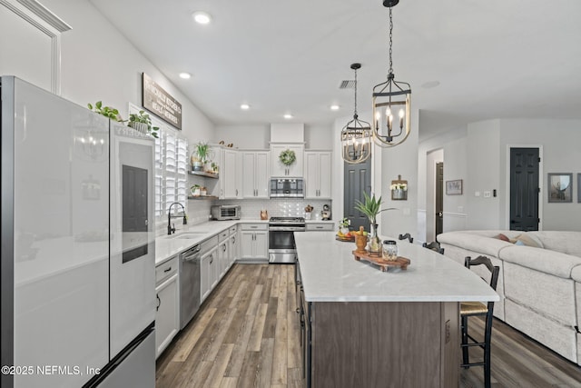 kitchen with a breakfast bar, open shelves, appliances with stainless steel finishes, open floor plan, and a sink