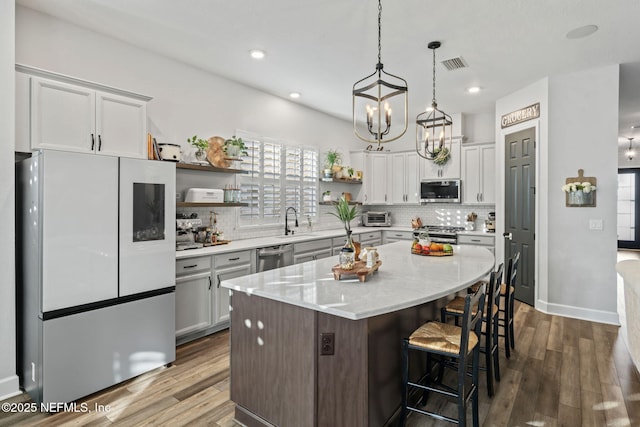 kitchen featuring tasteful backsplash, appliances with stainless steel finishes, open shelves, and a sink