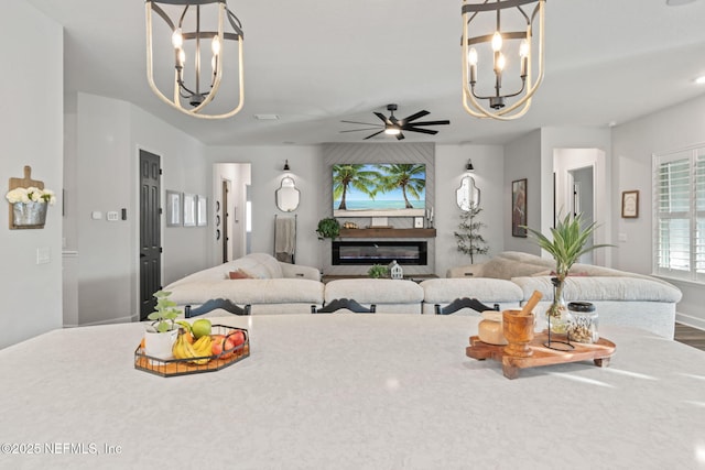 living area with a ceiling fan and a glass covered fireplace