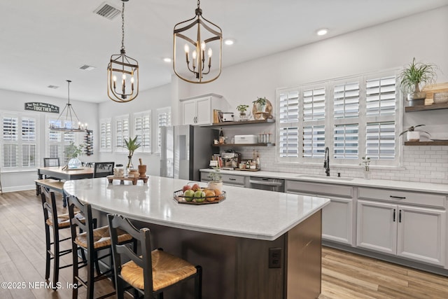 kitchen with open shelves, appliances with stainless steel finishes, a sink, and decorative backsplash