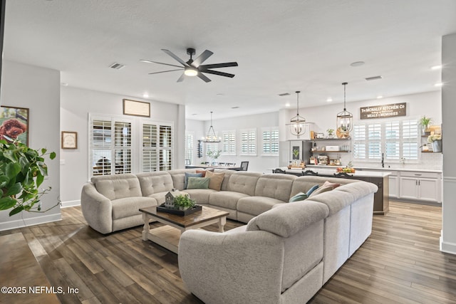 living area with baseboards, wood finished floors, visible vents, and recessed lighting