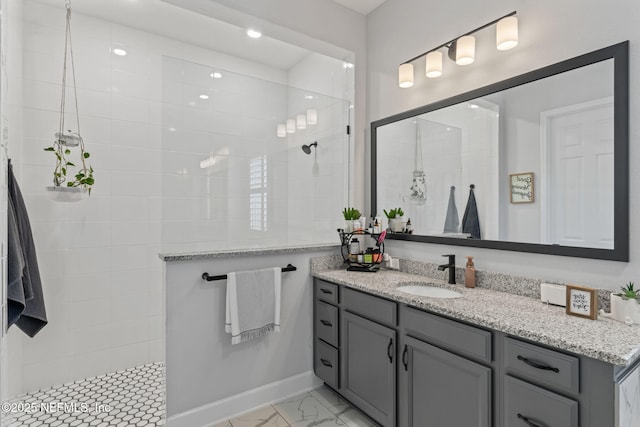 bathroom with marble finish floor, vanity, and walk in shower