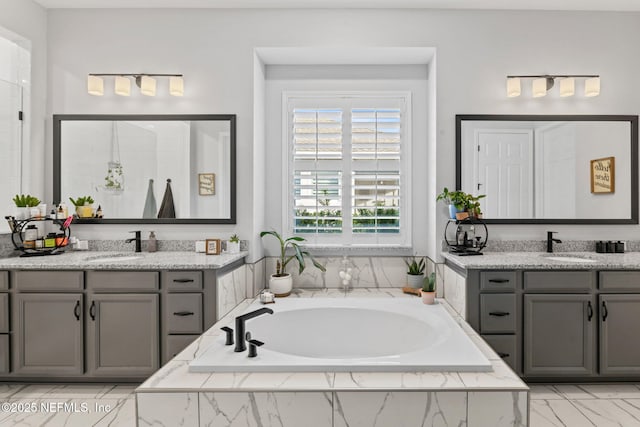 bathroom with two vanities, a garden tub, and a sink