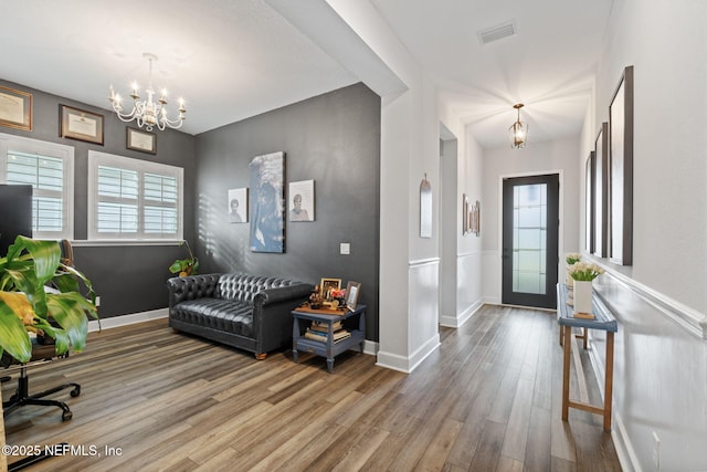 foyer entrance with a chandelier, visible vents, baseboards, and wood finished floors