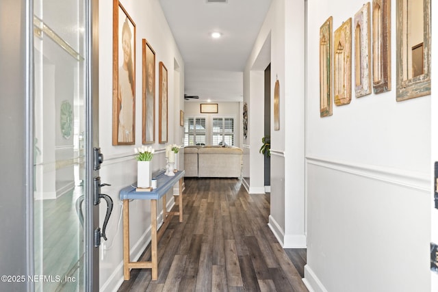 hallway featuring visible vents, baseboards, and dark wood-type flooring