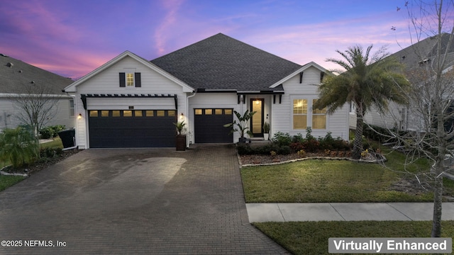 view of front of house with a shingled roof, a front yard, decorative driveway, and an attached garage