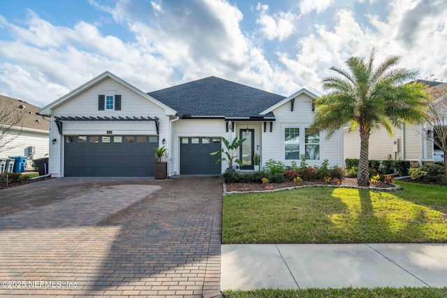 view of front of house featuring a garage, a front lawn, decorative driveway, and roof with shingles