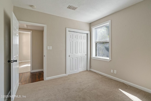 unfurnished bedroom featuring carpet flooring, a textured ceiling, and a closet