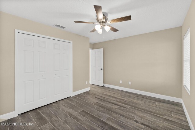 unfurnished bedroom featuring ceiling fan, dark wood-type flooring, and a closet