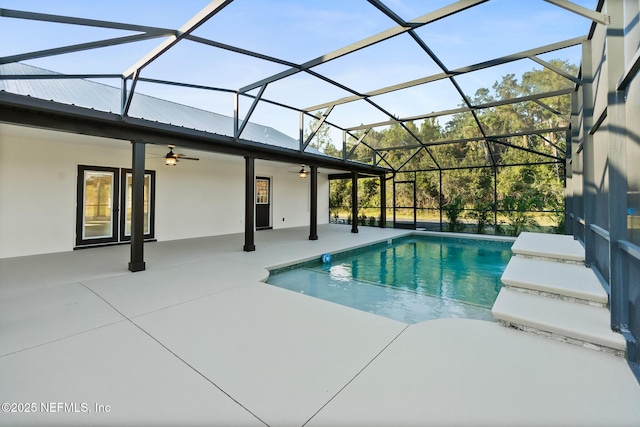 view of swimming pool featuring glass enclosure, ceiling fan, and a patio area