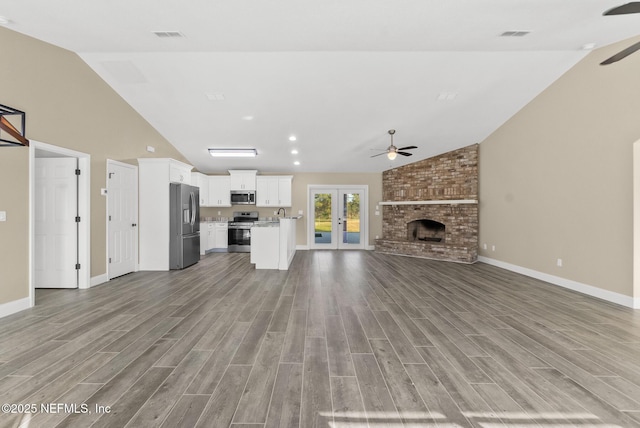 unfurnished living room featuring hardwood / wood-style flooring, ceiling fan, a brick fireplace, and vaulted ceiling