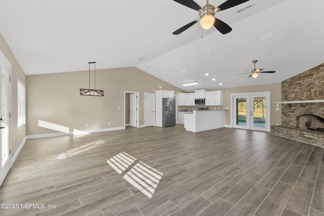 unfurnished living room featuring a fireplace, ceiling fan, french doors, and lofted ceiling