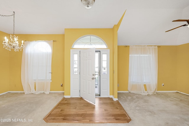 foyer entrance featuring ceiling fan with notable chandelier and carpet floors