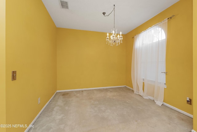 carpeted empty room featuring a chandelier