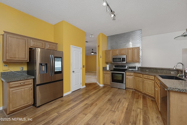 kitchen featuring ceiling fan, sink, stainless steel appliances, light hardwood / wood-style floors, and a textured ceiling