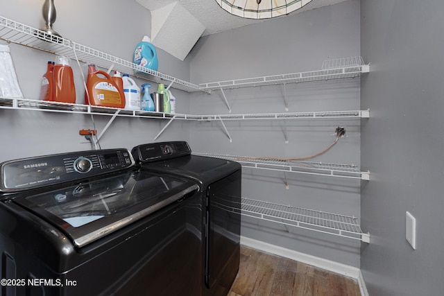 clothes washing area featuring washing machine and dryer and hardwood / wood-style flooring