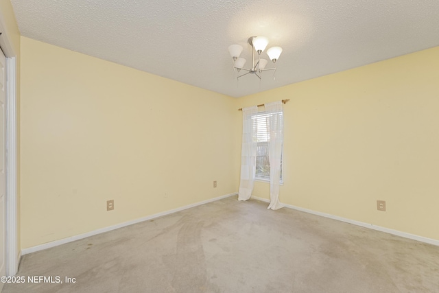 carpeted empty room with a chandelier and a textured ceiling