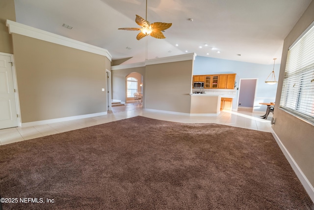 unfurnished living room with ceiling fan, light tile patterned floors, crown molding, and a wealth of natural light