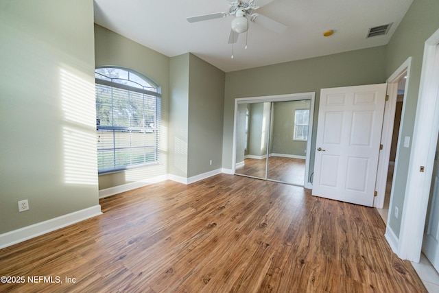 unfurnished bedroom with hardwood / wood-style floors, ceiling fan, and a closet