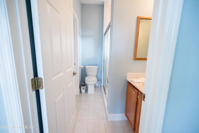 bathroom featuring tile patterned flooring, vanity, toilet, and an enclosed shower