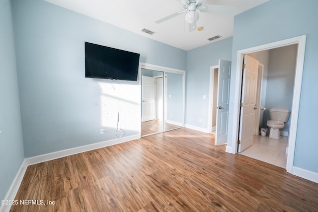 unfurnished bedroom featuring light wood-type flooring, a closet, ensuite bathroom, and ceiling fan