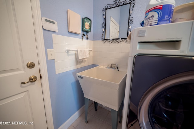 clothes washing area with tile patterned flooring, washer / dryer, and sink